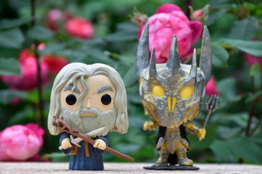 Büyücü Gri Gandalf ve Yüzüklerin Efendisi 'ndeki Karanlık Lord Sauron' un aksiyon figürleri. Gizemli karamsar bahçe, kırmızı güller.