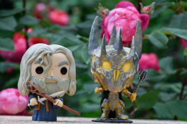Büyücü Gri Gandalf ve Yüzüklerin Efendisi 'ndeki Karanlık Lord Sauron' un aksiyon figürleri. Gizemli karamsar bahçe, kırmızı güller.