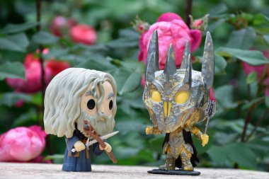 Büyücü Gri Gandalf ve Yüzüklerin Efendisi 'ndeki Karanlık Lord Sauron' un aksiyon figürleri. Gizemli karamsar bahçe, kırmızı güller.
