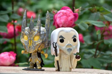 Kara Lord Sauron ve Yüzüklerin Efendisi 'ndeki Beyaz Büyücü Saruman' ın aksiyon figürleri. Gizemli karamsar bahçe, kırmızı güller.