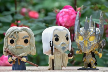 Gri Gandalf 'ın aksiyon figürleri, Beyaz Saruman ve Yüzüklerin Efendisi' ndeki Sauron. Gizemli karamsar bahçe, kırmızı güller.