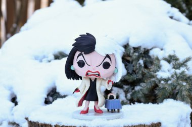 101 Dalmaçyalı animasyon filmindeki kötü karakter Cruella de Vil 'in Funko Pop aksiyon figürü. Kış, köknar ağacının dallarında bembeyaz kar.