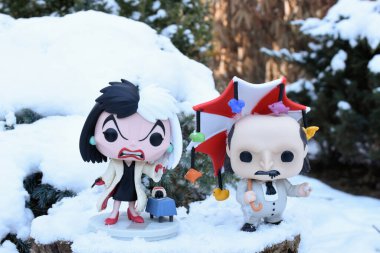 Disney filmi 101 Dalmaçyalı 'dan Cruella ve Batman' den Penguen 'in aksiyon figürleri. Kış, ağaç kütüğü, köknar dallarında yumuşacık kar.