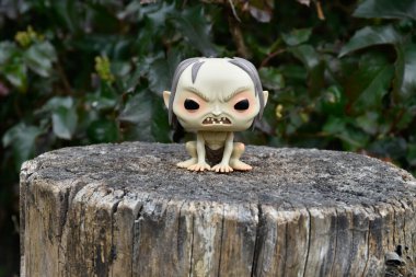 Gollum 'un fantezi filmi Yüzüklerin Efendisi' ndeki Funko Pop figürü. Karanlık orman, ağaç kütüğü, yeşil yapraklar..