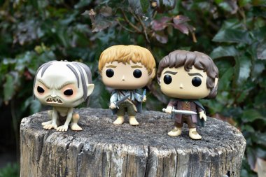 Gollum, Sam ve Frodo 'nun fantezi filmi Yüzüklerin Efendisi' ndeki Funko Pop aksiyon figürleri. Karanlık orman, ağaç kütüğü, yeşil yapraklar..