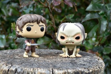 Fantezi filmi Yüzüklerin Efendisi 'ndeki Hobbit Frodo ve Gollum' un aksiyon figürleri. Karanlık orman, ağaç kütüğü, yeşil yapraklar..