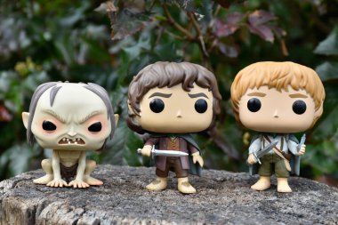 Gollum, Frodo ve Sam Hobbit 'in fantezi filmi Yüzüklerin Efendisi' ndeki Funko Pop aksiyon figürleri. Karanlık orman, ağaç kütüğü, yeşil yapraklar..