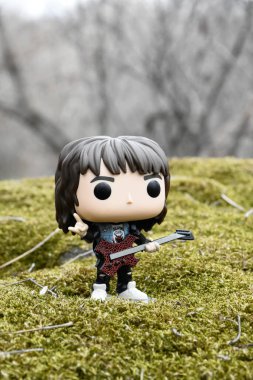 Korku dizisi Stranger Things 'ten Eddie Munson' ın funko pop aksiyon figürü. Yeşil yosunlu kayalar, vahşi orman, vadi, atmosferik yer. 