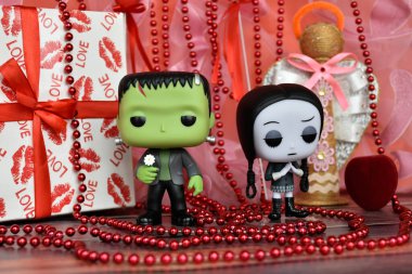 Funko Pop action figures of Frankenstein's monster and Wednesday Addams. Valentine's Day, handmade angel, gift box, necklace, red ribbons, hearts, romance.