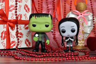 Funko Pop action figures of Frankenstein's monster and Wednesday Addams. Valentine's Day, handmade angel, gift box, necklace, red ribbons, hearts, romance.