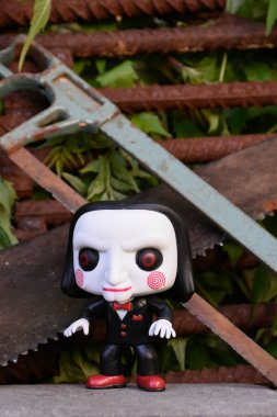 Billy the Puppet 'ın popüler korku filmi Testere' deki Funko Pop figürü. Ürkütücü terk edilmiş bir yer, paslı metal barlar, eski testereler..