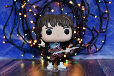 Popüler korku dizisi Stranger Things 'ten Eddie Munson' ın funko pop aksiyon figürü. Mavi sisli arka plan, renkli ışıklar, gizemli bir yer..