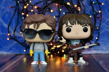 Popüler korku dizisi Stranger Things 'ten Steve ve Eddie' nin aksiyon figürleri. Mavi sisli arka plan, renkli ışıklar, perili, gizemli bir yer..