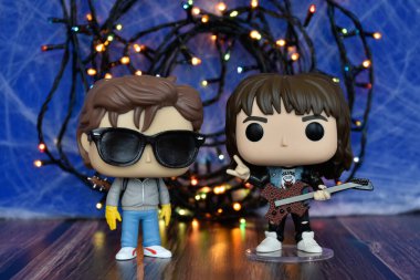 Popüler korku dizisi Stranger Things 'ten Steve ve Eddie' nin aksiyon figürleri. Mavi sisli arka plan, renkli ışıklar, perili, gizemli bir yer..