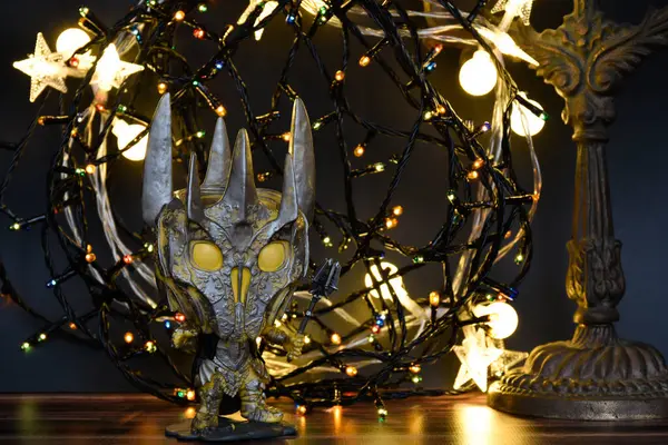 Yüzüklerin Efendisi filmindeki Karanlık Lord Sauron 'un aksiyon figürü Funko Pop. Renkli çelenk ışıkları, sıcak ışıklandırma, siyah arka plan, kasvetli bir yer.. 