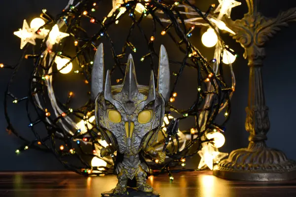 Yüzüklerin Efendisi filmindeki Karanlık Lord Sauron 'un aksiyon figürü Funko Pop. Renkli çelenk ışıkları, sıcak ışıklandırma, siyah arka plan, kasvetli bir yer.. 
