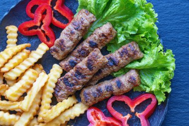 Balkan mutfağı. Cevapi - ızgara et - siyah tabakta sebzeli