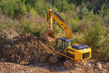 Dağlardaki inşaat yolu boyunca küçük sarı çizgili kazıcı. Karadağ