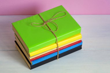 Beyaz kırsal masada iple bağlanmış renkli kitaplar yığını. Boşluğu kopyala