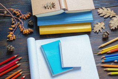 Autumn, okula dön. Ders kitapları, renkli kalemler, defterler ve kırsal masada sonbahar yaprakları. Boşluğu kopyala