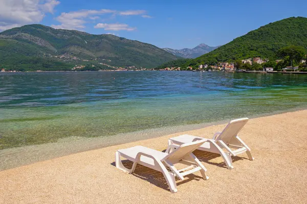 Güzel güneşli Akdeniz manzarası. Karadağ, Adriyatik Denizi. Tivat şehri yakınlarındaki Kotor Körfezi manzarası. Kumsalda iki şezlong.