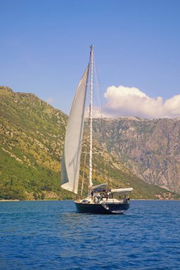 Güneşli yaz gününde güzel Akdeniz manzarası. Suyun üstünde beyaz yelkenli. Tatiller, eğlence, spor kavramları. Karadağ, Adriyatik Denizi, Kotor Körfezi