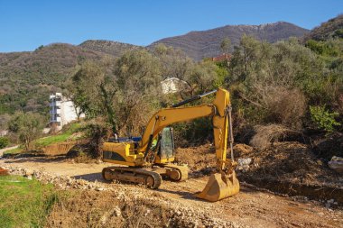 Dağlarda yol yapımı. Sarı çizgili kazıcı katları kayalık yol. Karadağ, Dinarik Alpler
