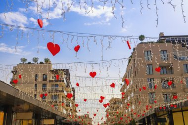 Işıklı çelenkler ve mavi gökyüzüne karşı kırmızı kalp şeklinde süslemeler. Karadağ, Tivat kenti