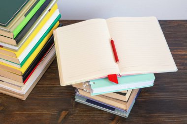 Renkli kitaplar yığını ve karanlık kırsal masada açık bir defter. Okula dönelim. Boşluğu kopyala