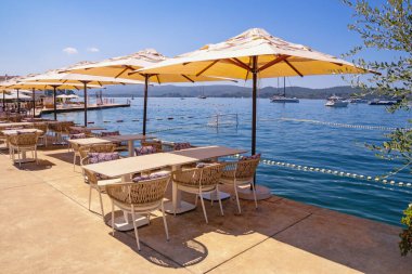 Yaz tatili. Karadağ, Adriyatik Denizi, Kotor Körfezi. Güneşli bir günde Tivat şehrinin setinde küçük bir kafe ve sahil.