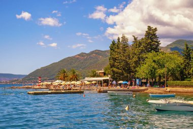 Tivat, Karadağ - 30 Temmuz 2025: Güzel Akdeniz yazı manzarası. Karadağ, Adriyatik Denizi. Tivat şehri yakınlarındaki Kotor Körfezi 'nin manzarası. Şezlongları ve plaj şemsiyeleri olan bir plaj. Tatil kavramı 