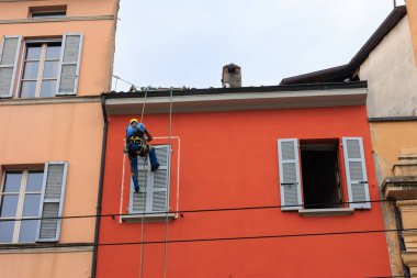 Evin ön cephesini boyamak için ipe asılmış bir işçi. Parma, İtalya _ 04 Ekim 2022 