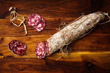Piacenza salami cut into slices on wooden table