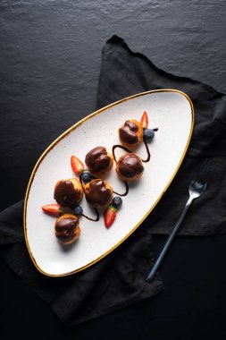 Çikolatalı kremalı ve çilekli tabak. koyu arkaplan