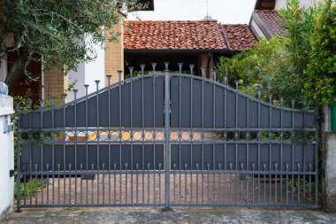 Bir kır evinin garaj yoluna açılan metal bir kapı görüntüsü.