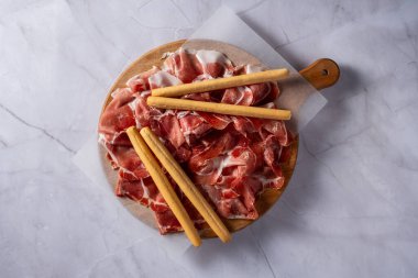 Üst tabakta San Daniele ham jambonu ve mermer tepeli galeta var.