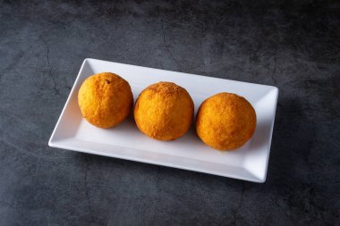 Koyu arkaplanlı kızarmış arancini tabağı. İtalyan pirinç topları.