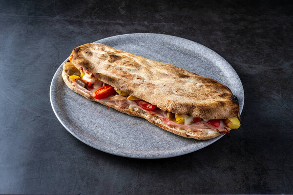 plate with traditional Italian panuozzo sandwich. Dark background