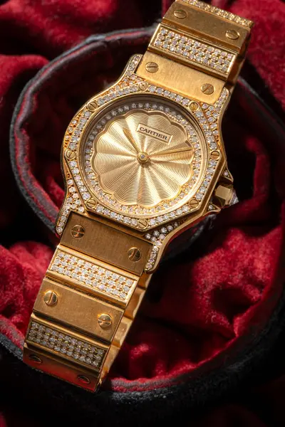 Cartier saat, Santos Bayan Evren modeli. Otomatik saat, sarı altın çanta, kırmızı kumaş arka planda 2965 'ten bahsediyor. Milan mı? İtalya _ 12 Kasım _ 2024