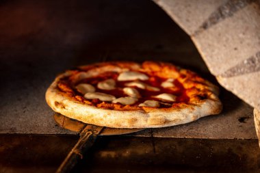 Fırından metal kabuklu sıcak pizza çıkartılıyor fırından. Geleneksel yemek içeriği.