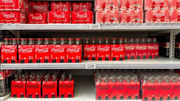 Bir mağaza rafında çeşitli Coca-Cola şişeleri ve kutu paketleri sergileniyor. Udine, İtalya. 8 Haziran 2025.