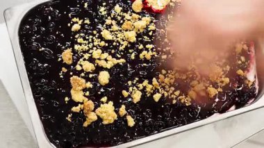 Dondurmacı, ezilmiş amaretti bisküvilerini bir küvi zanaatkar dondurmanın üstüne koyar..