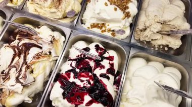 Dondurma tezgahında sergilenen çeşitli aromalı sanat dondurmaları renkli ve kremalı tatlılar sergiliyor..