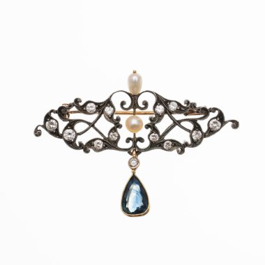 Zarif sarı altın ve gümüş broş, parlak kesilmiş elmaslar ve safir bir damla ile süslenmiş. Beyaz bir arkaplanda izole edilmiş fotoğraf.