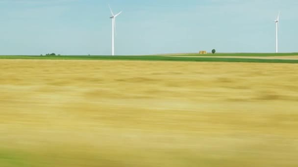 穿过田野的路上有车 周围有黄色的草地 远处可以看到风力涡轮机 高质量的4K镜头 — 图库视频影像