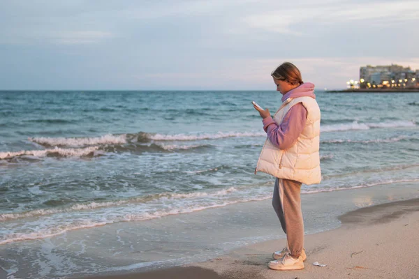 Elinde Telefonla Sahilde Mavi Denizle Bekleyen Heyecanlı Bir Kızın Portresi — Stok fotoğraf