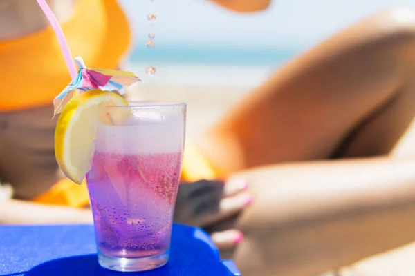 stock image a pink cocktail close-up on the beach, a girl in a swimsuit lies on a sun lounger next to it stands a close-up of a pink color cocktail. The concept of relaxing on the beach. High quality photo