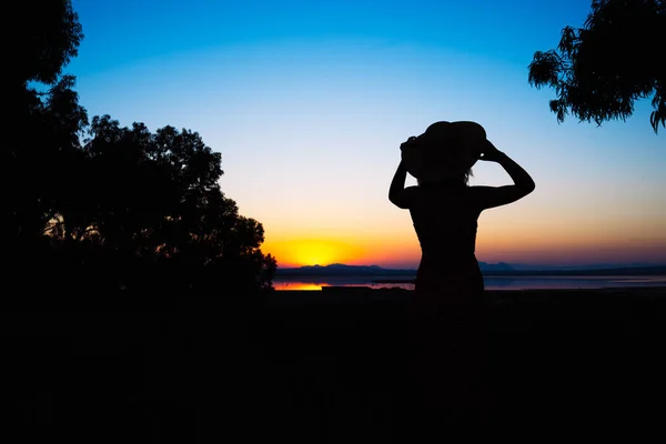 公園の日没時にドレスと帽子の女の子のシルエット 少女は日没を見ます 碑文のための場所があります 高品質の写真 — ストック写真