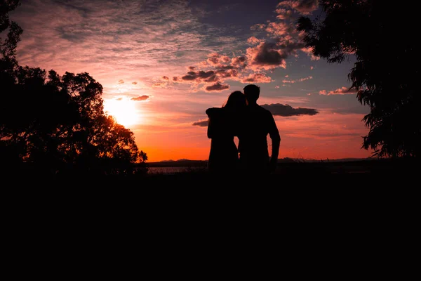 一对恋人在夕阳西下的轮廓映衬着大自然 有一处题词的地方 男人抱着女孩 一对幸福的夫妻的轮廓映衬着 高质量的照片 — 图库照片