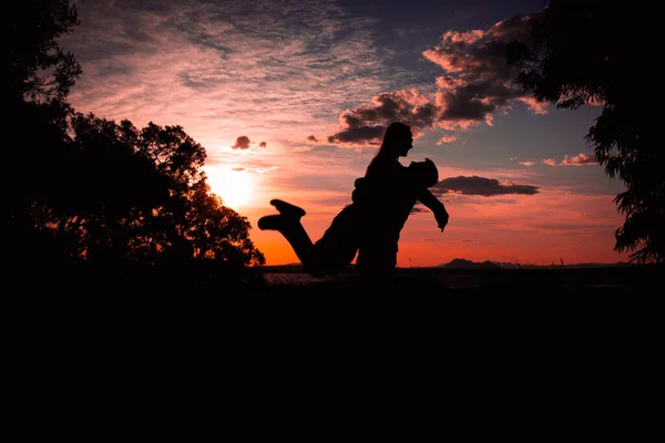 silhouette of a couple in love at sunset against the backdrop of nature, there is a place for the inscription, the guy is holding the girl in his arms, a happy couple silhouette. High quality photo